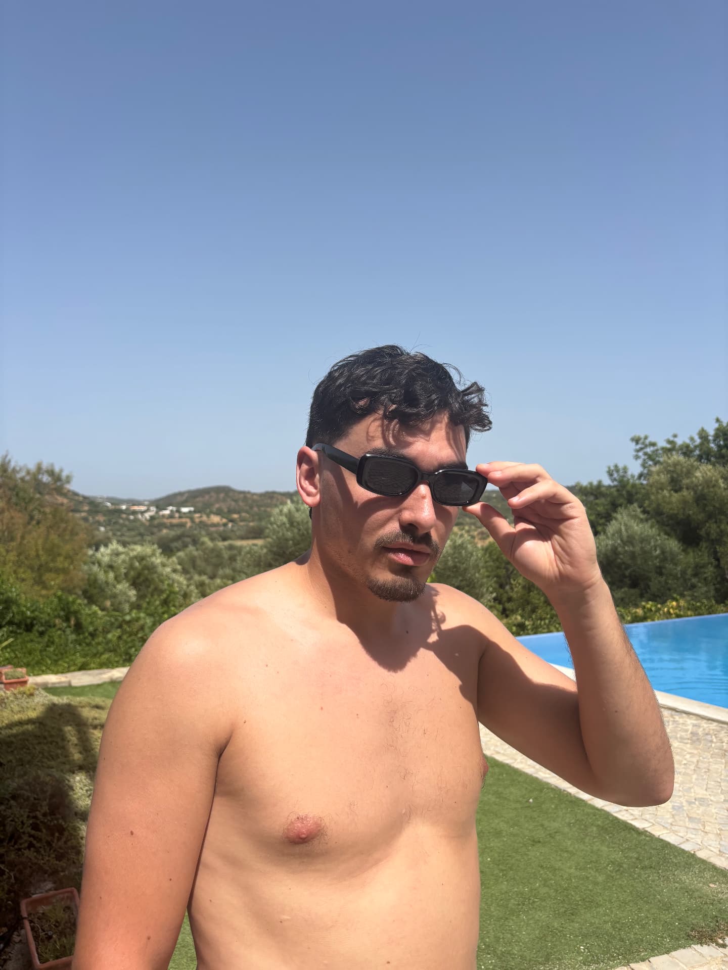 Man lowering the sunglasses by a pool